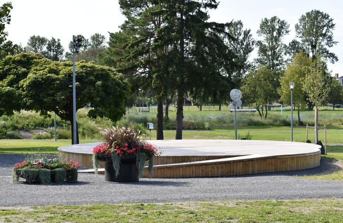 Rund träscen i Agda Östlunds park med planteringar i förgrunden.